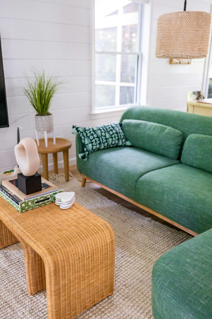 A stylish living room featuring a green sofa and rattan table, perfect for a relaxed home vibe.